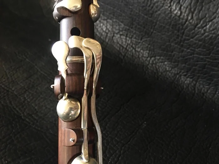 Close view of a blackwood flute with silver block-mounted keys on dark leather.